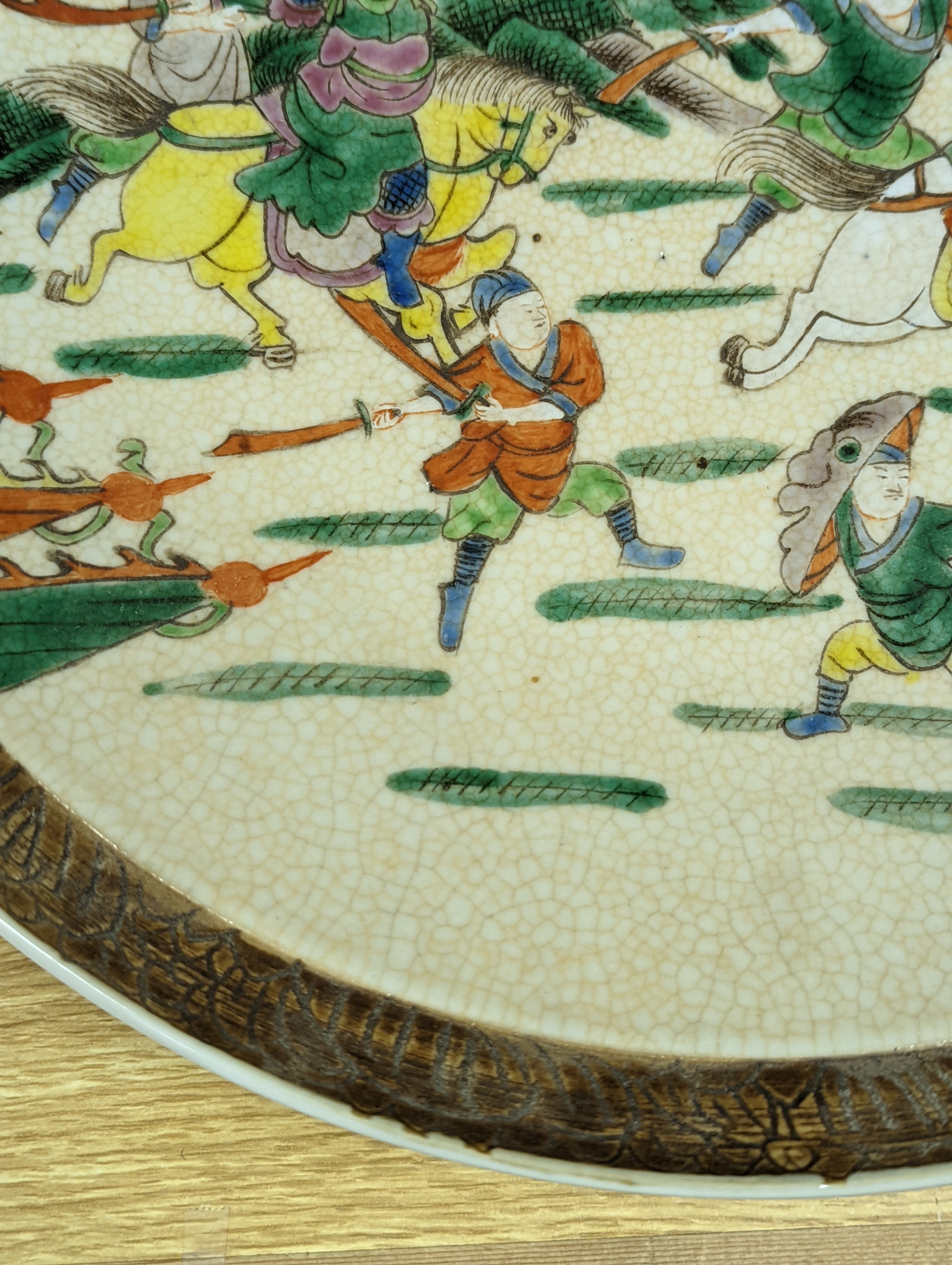 A Chinese crackle glaze dish, early 20th century, depicting a battle scene 33cm
